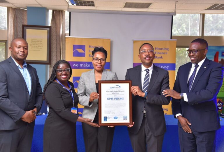 Top Housing Finance Bank and Certi-Trust executives pose for a group photo with the ISO certificate during the handover in Kololo